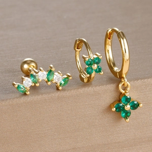 Detail of clover earring set with green crystals and gold plating on a metal stand