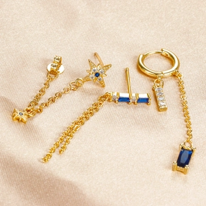 Detailed shot of golden star chain tassel earrings with zircon inlay on champagne silk