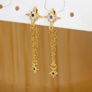 Detail of gold star earrings with blue zircon center and elegant long chain tassels