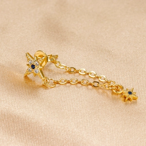 Detailed close-up of golden North Star earrings with blue gems on silk fabric