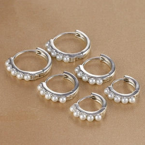 Set di tre paia di orecchini a cerchio in argento con perle su sfondo dorato testurizzato