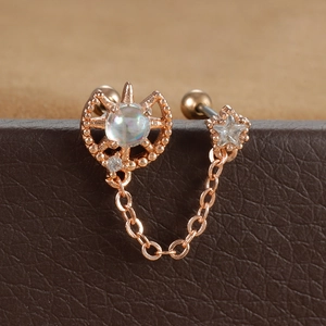 Détail macro d'une boucle d'oreille rose gold avec roue solaire, opale et étoile