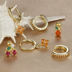 Luxury gold clover and cherry zircon earring set displayed on elegant champagne velvet