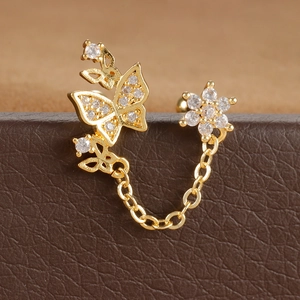Vue détaillée de boucles d'oreilles fleur et papillon dorées avec zircons et chaîne