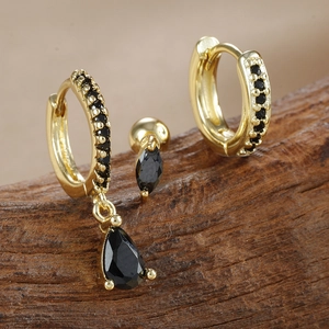 Primer plano de pendientes dorados con circonita negra en gota y detalles de corte marquesa
