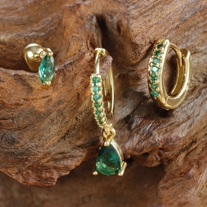 Detalle macro del conjunto de pendientes dorados con circonitas en color verde esmeralda
