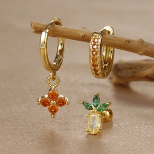 Detail of clover and fruit earrings set with orange and yellow zircon on wood