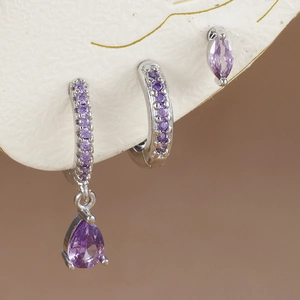 Detalle de pendientes de gota con circón púrpura y tachuelas en tablero texturizado