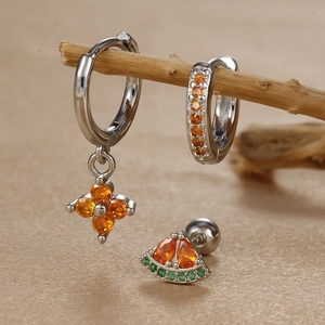 Macro shot of silver clover and watermelon earrings set with orange cubic zirconia stones