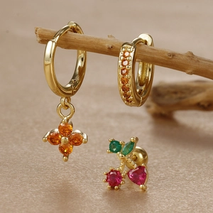 Close-up of gold clover earrings and cherry stud jewelry set with orange zircon