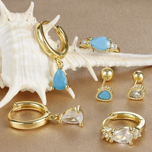 Parure de bijoux dorés avec pierres bleues en goutte et zircon sur satin