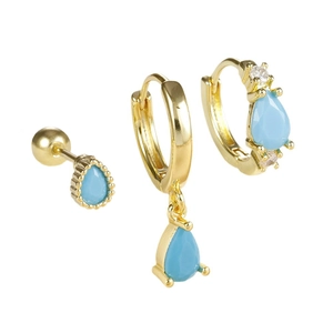 Ensemble de trois boucles d'oreilles dorées avec zircons gouttes bleu clair sur fond blanc