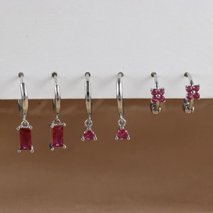 Detailed view of silver stud earrings set featuring dark red rectangle and flower crystals