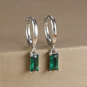 Macro detail of emerald green zircon rectangle drop earrings in silver finish