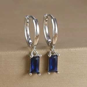 Macro shot of silver-plated earrings featuring deep blue rectangular zircon drops in 4-prong setting