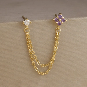 Dettaglio di orecchini a catena placcati oro con gemme viola e zirconi trasparenti