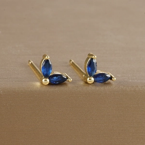Macro shot of gold-plated leaf earrings with marquise blue zircon in a claw setting