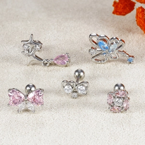 Detailed view of silver bow and star cartilage piercings with pink and blue zircons
