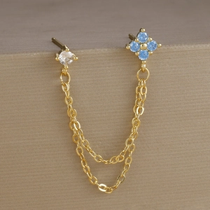 Dettaglio orecchino a catena in oro con fiore in zircone blu e pietra di zircone chiara