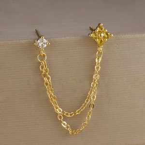 Dettaglio di orecchini a catena in oro con borchia in zircone per doppi fori orecchio