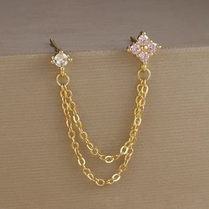 Dettaglio di orecchini asimmetrici placcati in oro con zirconi cubici rosa e bianchi