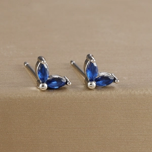 Macro shot of marquise-cut blue gemstone leaf earrings on a golden brushed base