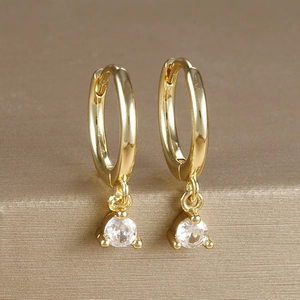 Detail macro view of gold plated hoop earrings with round zircon stones and polished finish