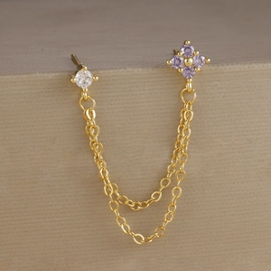 Dettaglio di doppi orecchini dorati con fiore in zircone lavanda e catene sottili
