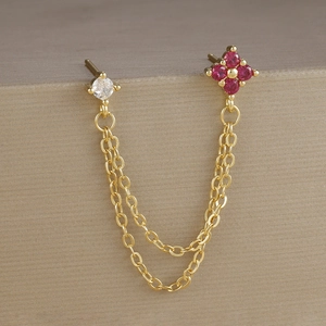 Dettaglio di orecchini a doppio foro placcati in oro con fiori di zircone rosso e bianco