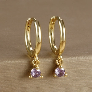 Detailed close-up of golden hoop earrings with lavender cubic zirconia gemstone pendants