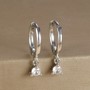 Close-up of silver-tone hoop earrings featuring a single round zircon on a metal stand