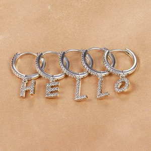 Silver HELLO letter hoop earrings set with micro-pave cubic zirconia on silk background