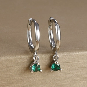Macro detail of silver drop earrings featuring claw-set round green zircon stones