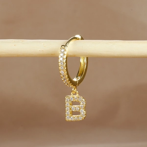 Macro shot of gold-plated earring with letter B pendant and micro-pave zircons