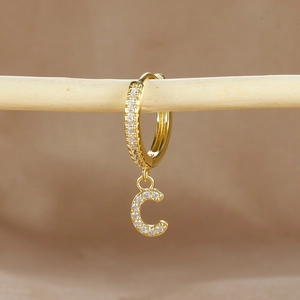 Close-up of gold-plated letter C earring featuring micro-pave cubic zirconia on wood bar