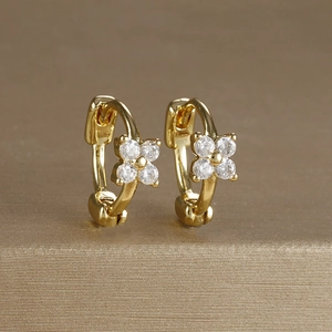 Close-up of gold-plated hoop earrings with zircon-inlaid flowers on a textured base