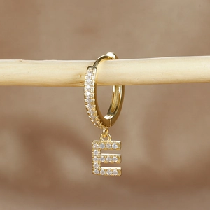 Macro shot of gold-plated letter E hoop earring with micro-pawned cubic zirconia
