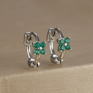 Macro shot of clover earrings with green zircon stones on champagne gold metal stand