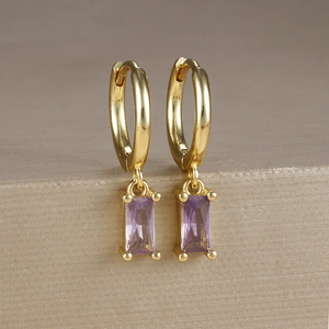 Dettaglio macro di orecchini a cerchio placcati oro 18k con pietre di zircone viola