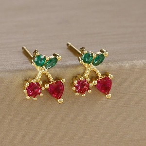 Macro shot of cherry-shaped stud earrings with red heart-shaped stones and gold plating