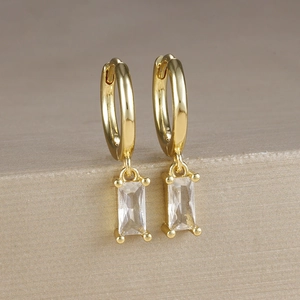 Dettaglio macro di orecchini a lobo in zircone quadrato placcati oro con frange geometriche