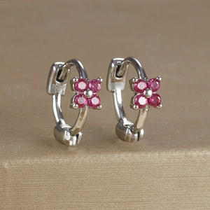 Macro shot of silver earrings with pink zircon flower pattern on champagne surface