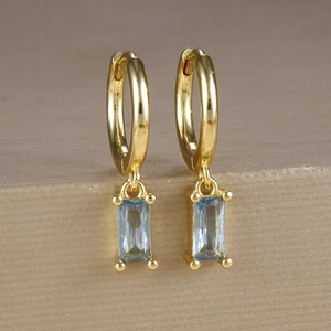 Dettaglio di orecchini geometrici placcati in oro con zircone blu e nappe a frangia