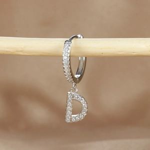 Macro view of silver letter D earring with micro-pave cubic zirconia on small hoop
