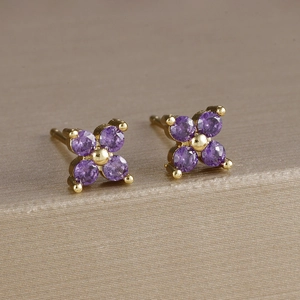 Vista macro di orecchini a fiore in oro con quattro petali di zircone viola