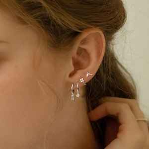 Silver-plated brass earrings set with square zircon crystals and floral studs on model