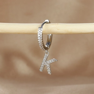 Detail view of silver hoop earring with iced out letter K pendant and cubic zirconia