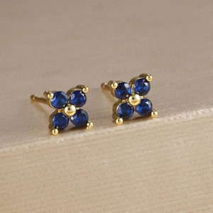 Dettaglio di orecchini a fiore in oro con zirconi blu su supporto di lusso elegante