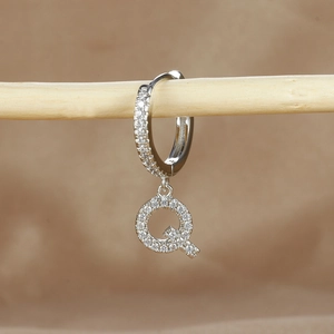 Detailed close-up of a silver hoop earring featuring a pavé zircon letter Q pendant