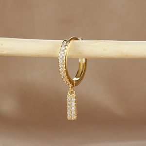 Macro detail of gold hoop earring with micro-p镶 pave zircon drop hanging on wood branch